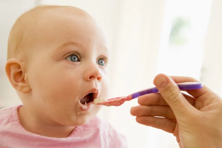 Mother feeding baby food to baby and it makes a face