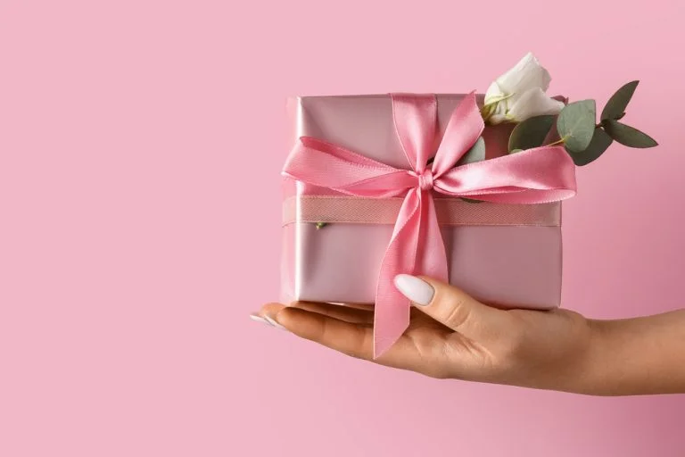 emale hand with beautiful gift box on color background, closeup